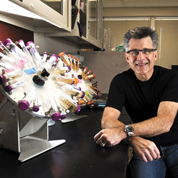 Jeff Brinker sits next to a cell-suspension wheel that contains bacteria suspended in media. (Photo by Randy Montoya)