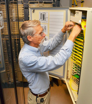 FIBER OPTIC A WINNER - Popular Science awarded Sandia its Grand Award for Engineering for its fiber optic network in the magazine’s Best of What’s New 2013 winners. In this photo for a Lab News story about the network in February, senior engineer Steve Gossage (9336) looks at fiber optic cable that replaced heavier and bulkier copper cable for high-speed communications throughout much of the Labs. (Photo by Randy Montoya)