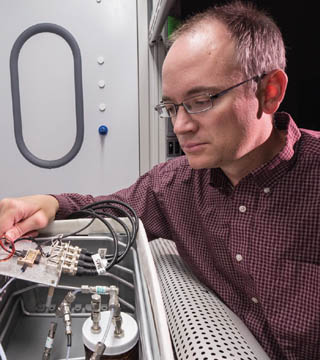 DETECTING HOMEMADE EXPLOSIVES  Chris Brotherton (6633) checks four tiny sensors in a test fixture, where he exposes the sensor to different environments and measures their response to see how they perform. Chris was principal investigator on a project aimed at detecting a common type of homemade explosive made with hydrogen peroxide. (Photo by Randy Montoya)