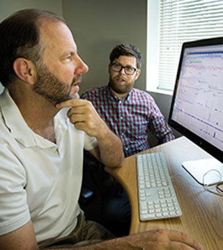 IDENTIFYING MECHANISMS BACTERIA USE — Sandia researchers Kelly Williams, left, and Corey Hudson (both 8633) view a segment of the Klebsiella pneumoniae genome around two genomic islands. The two researchers and their colleagues have identified several mechanisms that bacteria use to share genes and expand their antibiotic resistance.	(Photo by Dino Vournas)