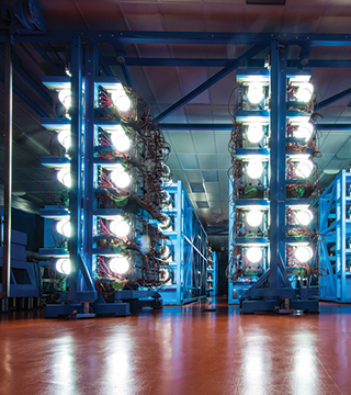 Twenty-centimeter disk amplifiers (shown here) used to energize 60 laser beams glow brightly at the 100-meter-long OMEGA laser at the University of Rochester’s Laboratory for Laser Energetics, while amplified light passes through the large tubes of Sandia’s Z-Beamlet laser (not shown), one of the most powerful in the world. Both lasers will experiment with more efficiently preheating fusion fuel to improve the output of Sandia’s MagLIF (Magnetized Liner Inertial Fusion) technique (Photo courtesy of University of Rochester)