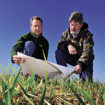 Mike Mitchell, (6765, left) and Don Schofield (4133) inspect the evapotranspirative cover of the Mixed Waste Landfill. (Photo by Randy Montoya)