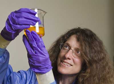 SANDIA RESEARCHER May Nyman investigates radioactive materials in a beaker of dissolved uranium and templates, from which crystals will grow. Her gloves, taped to her lab coat, effectively prevent any contact from possible spillage of the hot materials. The radioactivity of this particular mix is fairly low, on par with thorium lantern mantles sold in camping equipment shops. (Photo by Randy Montoya)
