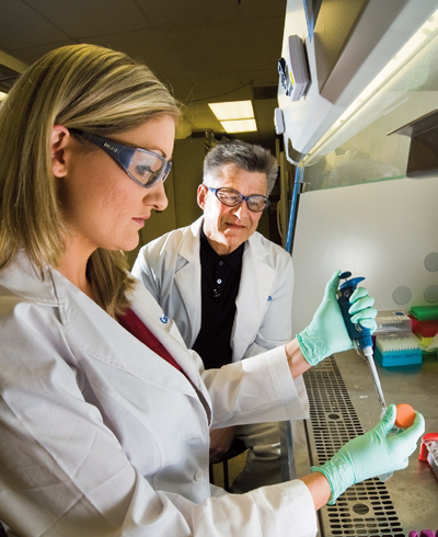 SANDIA HARRY S. TRUMAN post-doctoral fellow Carlee Ashley introduces a buffer into a protocell solution to dilute it as Sandia researcher and University of New Mexico professor Jeff Brinker watches.