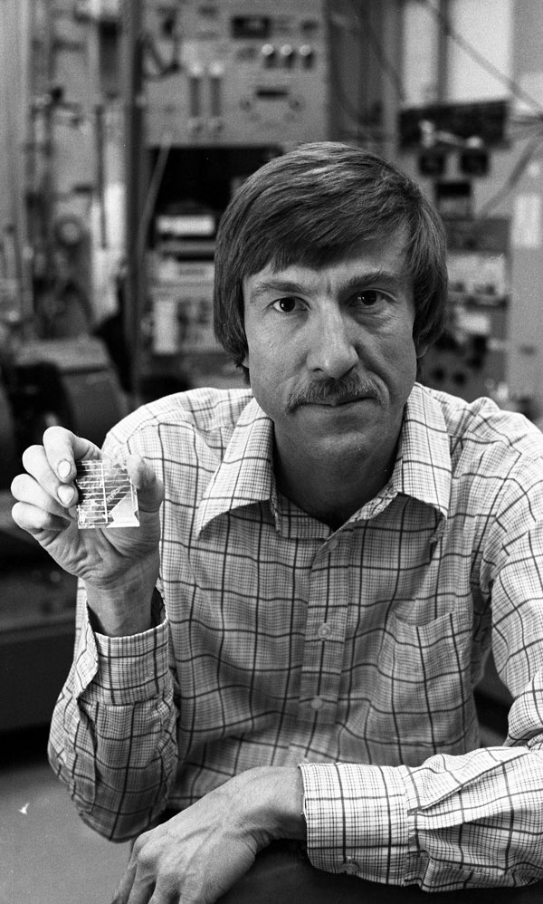 SOLAR REVOLUTION — Carl Seager displays an example of a polycrystalline silicon solar cell, in a 1984 file photo. Note that the light reflection differs on the surface of the various crystals in the material. Sandia developed the hydrogen passivation technique that improved the photovoltaic performance of this class of relatively inexpensive solar cells. (Photo courtesy of Sandia National Laboratories)