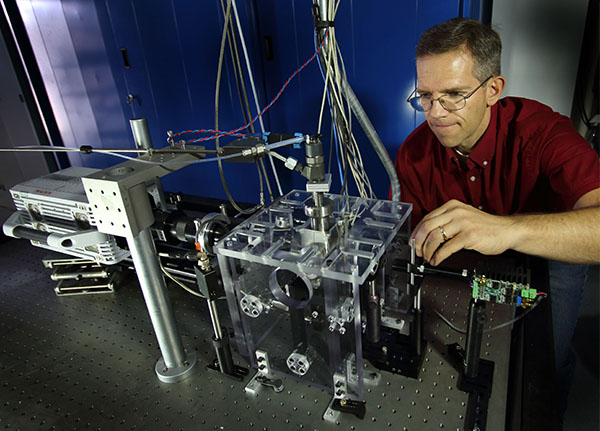 INJECTOR INSPECTION – Lyle Pickett (8362), who serves as the primary lead for the consortium at Sandia, examines a fuel injector with the nozzle modified for optical access. The internal geometry is the same size as a metal nozzle (hole less than 0.2 mm) and the injector operates at realistic pressures. (Photos by Dino Vournas)