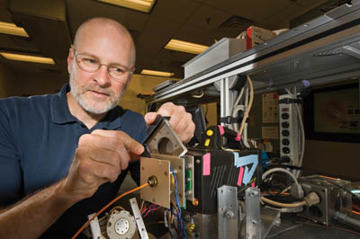 Explosive detection specialist Chuck Rhykerd snaps into place the metal screen at the heart of the next-generation explosive trace detection technology under development. (Photo by Randy Montoya) )