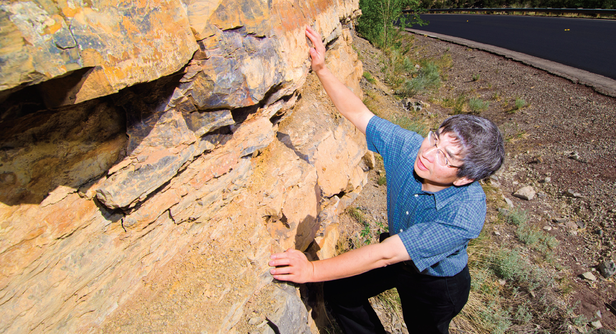 Yifeng Wang examines a sedimentary outcrop in Tijeras Canyon. Yifeng is lead author of a paper published recently in Nature Communications that offers new insights into pore size and distribution in horizontal slices of sedimentary rock. (Photo by Randy Montoya)