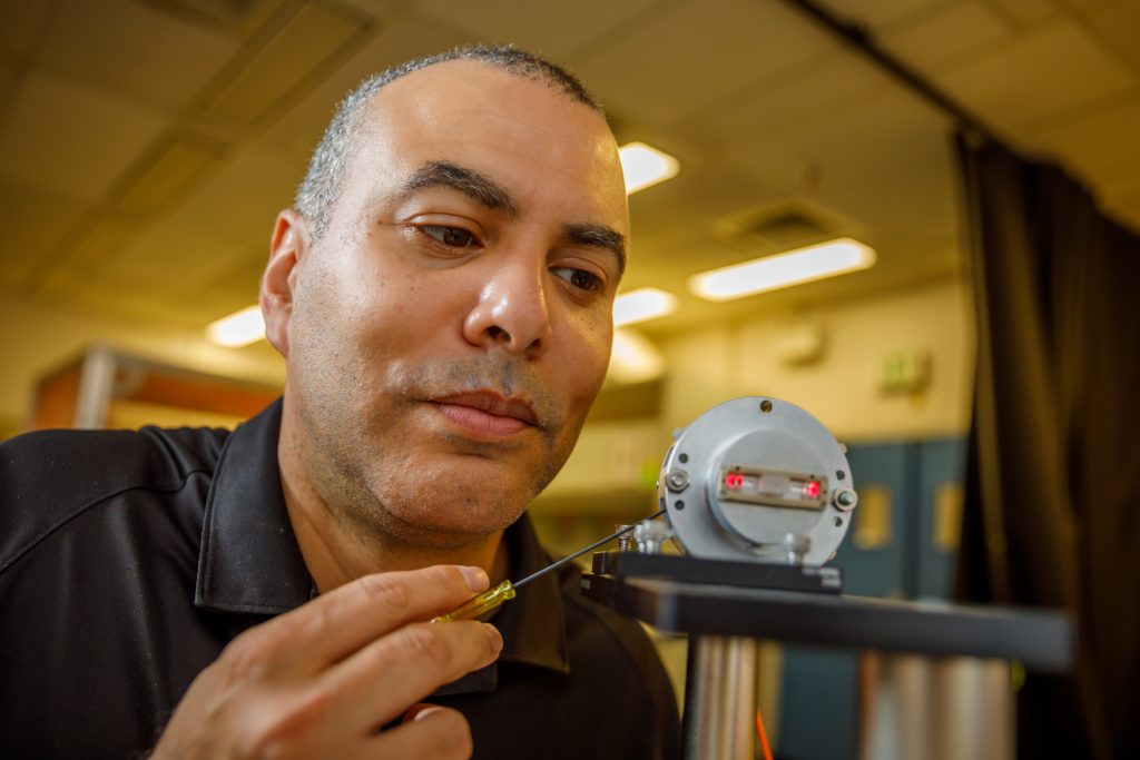 Image of Israel Owens holds optical sensor