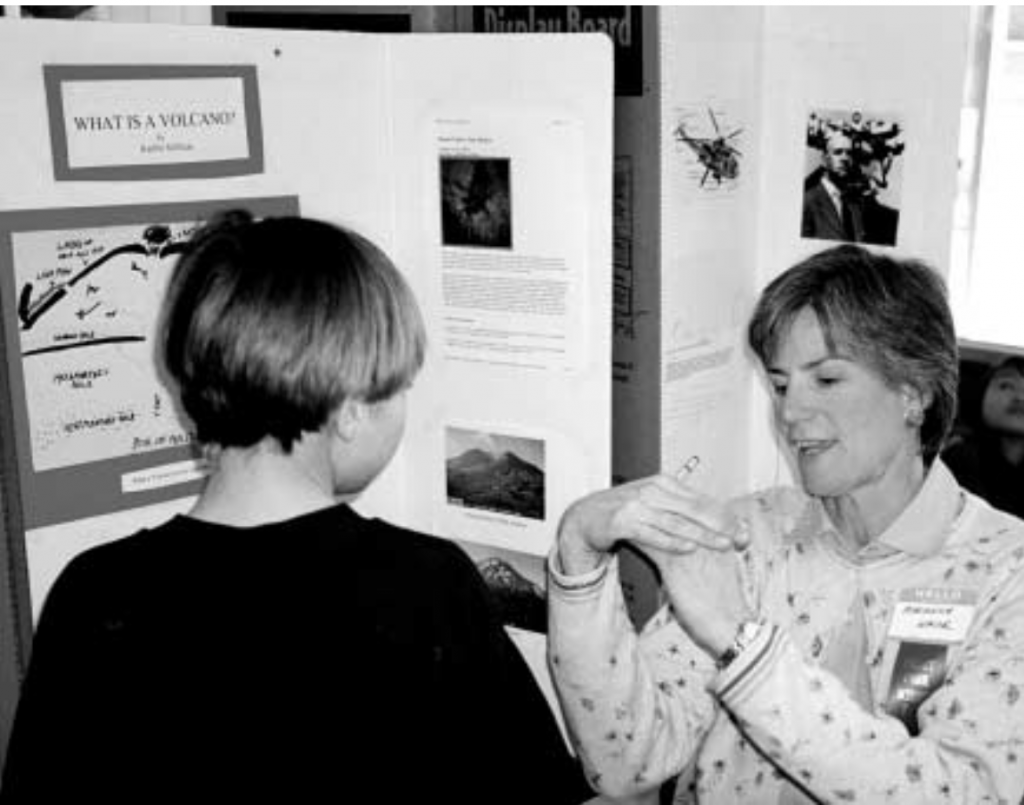 IT’S LIKE THIS — Sandia geophysicist Marianne Walck, Manager of Geophysical Technology Dept. 6116,explains the internal dynamics of a volcano to a fourth-grade student at Collette Park Elementary School in Albuquerque during the school’s Feb. 13 science fair. During science fair season, scores of Sandians volunteer their time and expertise as judges. (Photo by Randy Montoya)