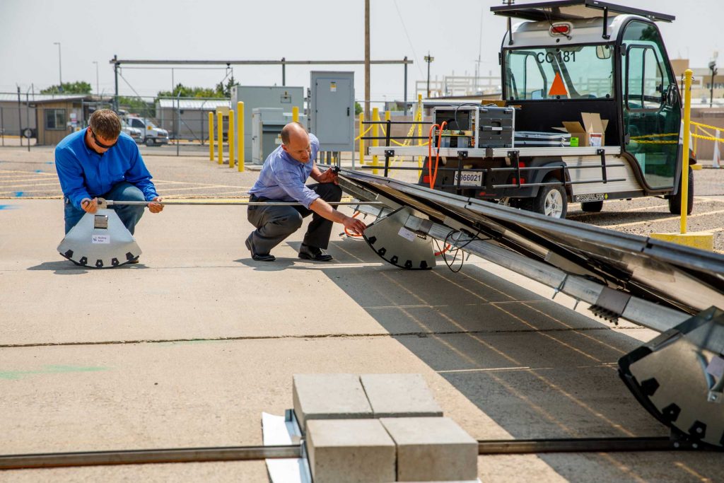 GAME-CHANGING DESIGN — Sandia technologist William Snyder and Rocking Solar CEO Darin Palmer adjust the actuator that moves the tracker rockers.