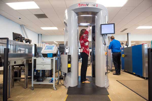 RESPONDING TO EMERGING NEEDS — A Pacific Northwest National Laboratory staffer stands in a traditional millimeter wave body scanner. “Screening has largely been unchanged for the last 20 years, and this project provides an opportunity to really transform how this technology is leveraged for national security and safety,” Sandia optical engineer Ed Jimenez said. (Photo by Andrea Starr, Pacific Northwest National Laboratory)