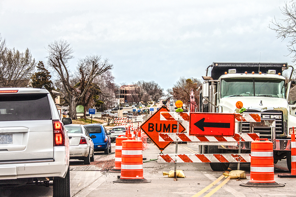 Image of Trucks and road equipment on road with one lane blocked to horizon in urban area an cars navigation the construction