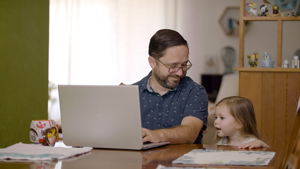 Image of Sandia staff member Joel Ortiz and his daughter while working at home