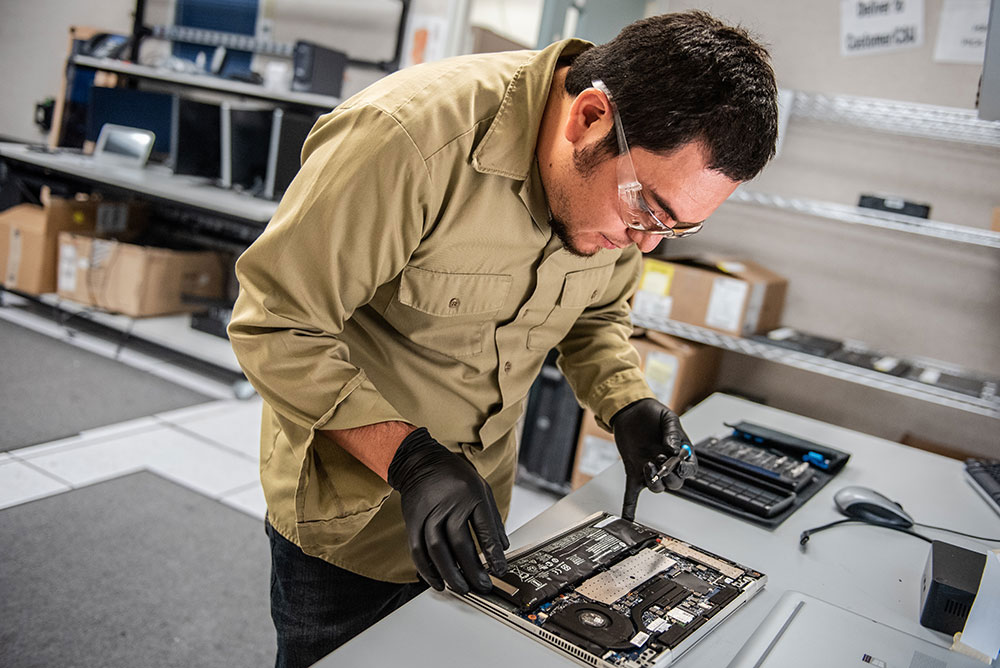 Image of Luis "Eddie" Lucero repairs a laptop