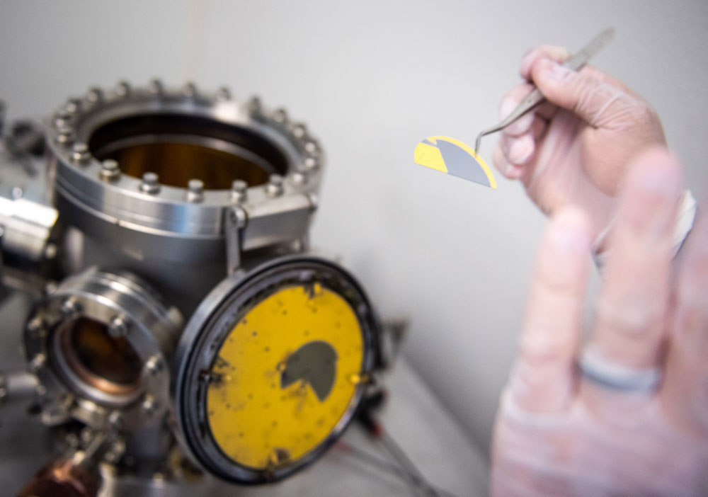 GOLDEN WAFER — Senior technologist Michael De La Garza removes a silicon wafer coated with gold that will be used for calibrating a thermal metal evaporator that he built at Sandia’s Center for Integrated Nanotechnologies. (Still from video by Kimberly Bassett)