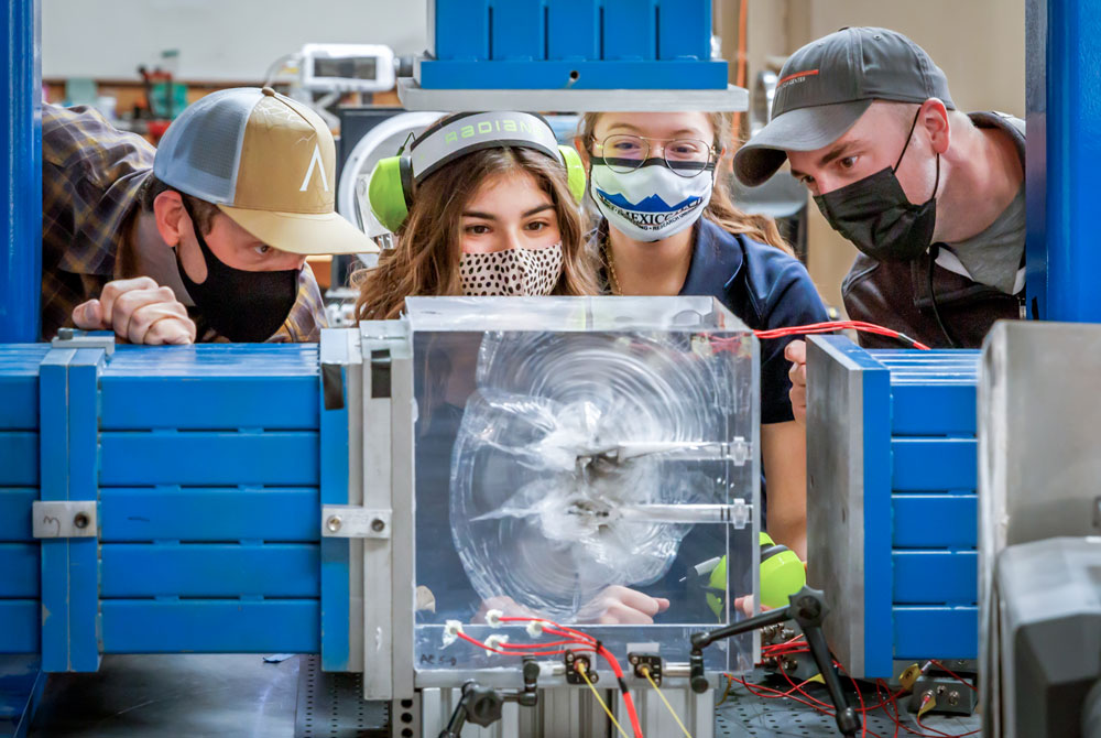 Image of Sandia engineers examine a plexiglass cube fractured by a small-scale explosion