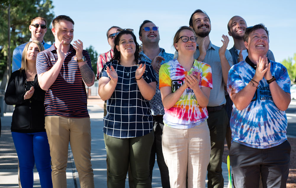 Image of Sandia staff members applaud as the Pride flag is raised for the first time at Sandia