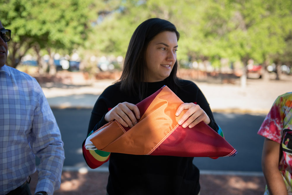 Image of Mary Guth, a board member of the Sandia Pride Alliance Network, passes a Pride flag