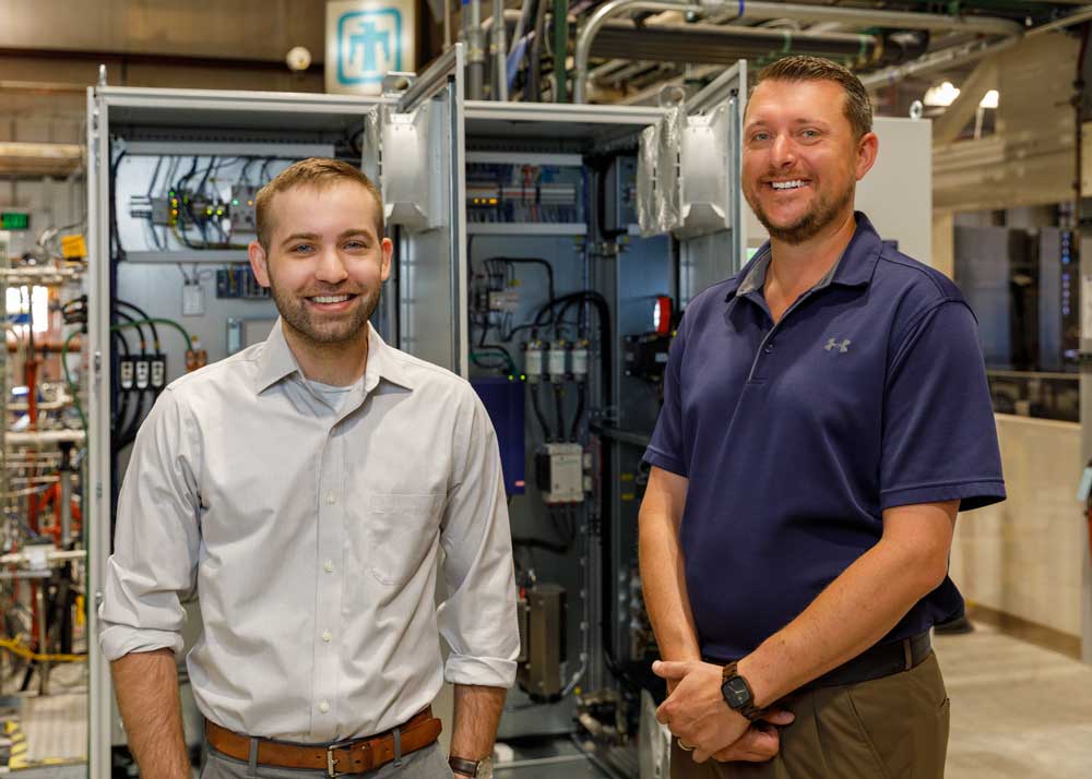 Image of Sandia mechanical engineers stand with controls system for new Brayton cycle test loop
