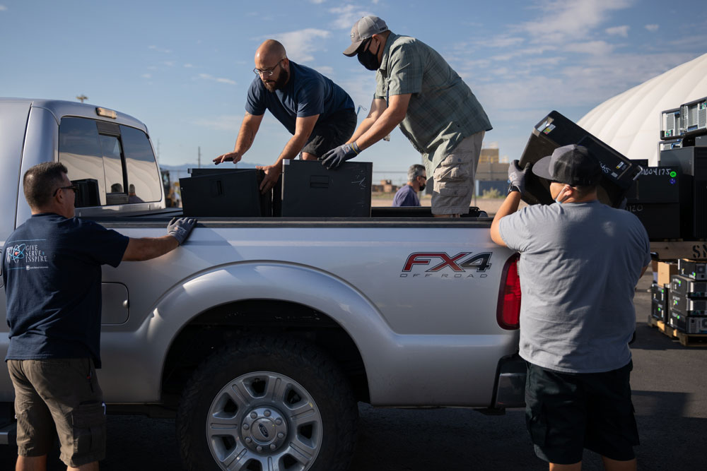 FILL ‘ER UP — Sandia Reapplication team members Benjamin Madrid, James Vigil, Greg Ulibarri and Gilbert Alvarado, left to right, load computers for the Early Childhood Academy in Albuquerque during Sandia’s Annual K-12 Computer Donation event.