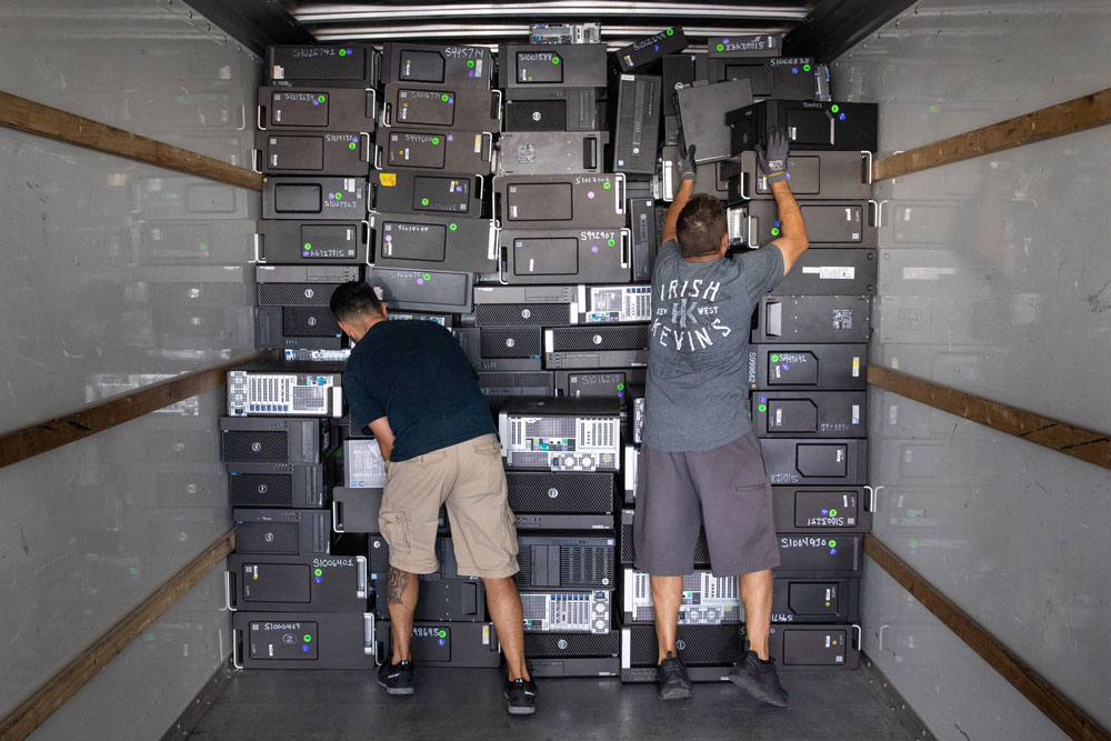 BY THE TRUCKLOAD — Martin Gonzales, left and Ron Baca begin to load a truck with computers for the Silver Consolidated School District during Sandia’s Annual K-12 Computer Donation event.
