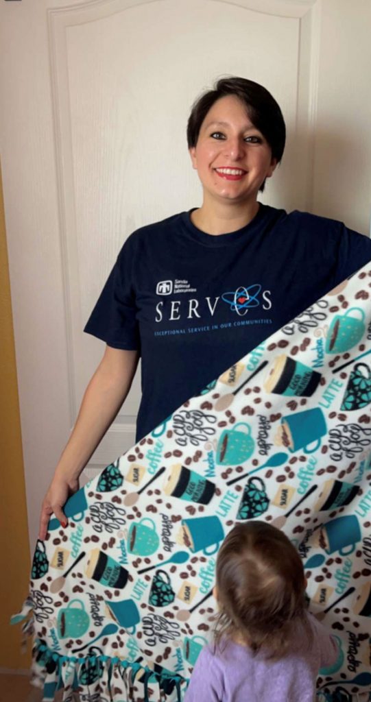 Image of Technologist Amelia Reyes displays a blanket she made that will be donated to a homeless family