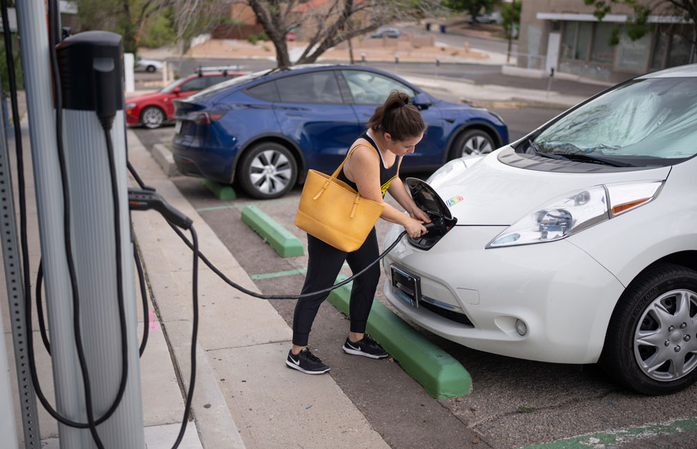 Image of Woman charges electric vehicle at charging station in Albuquerque