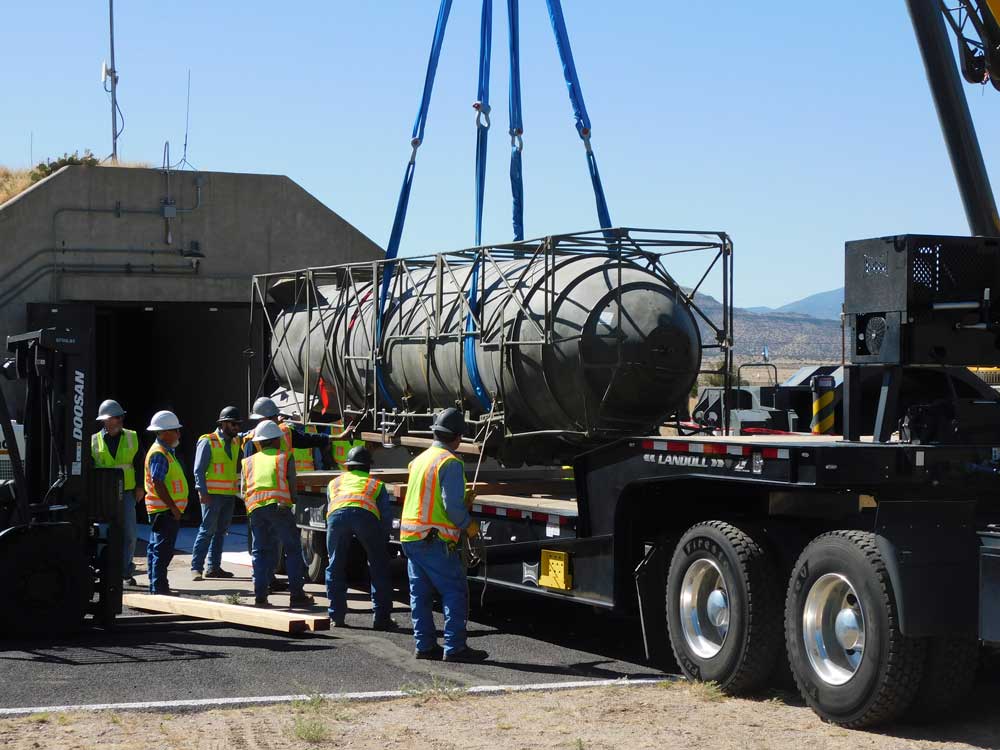 SECURE CARGO — Once harnessed, the team loads Mk-17 trainer by crane to a flatbed trailer for delivery. (Photo by John Korbin)