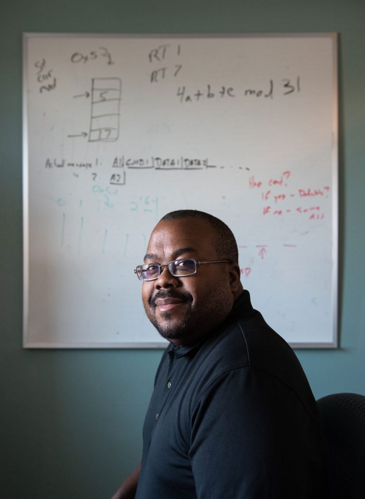 SKETCHING A DEFENSE — Sandia cybersecurity expert Chris Jenkins sits in front of a whiteboard with the original sketch of the moving target defense idea for which he is the team lead. When the COVID-19 pandemic hit, Chris began working from home, and his office whiteboard remained virtually undisturbed for more than two years. (Photo by Craig Fritz)