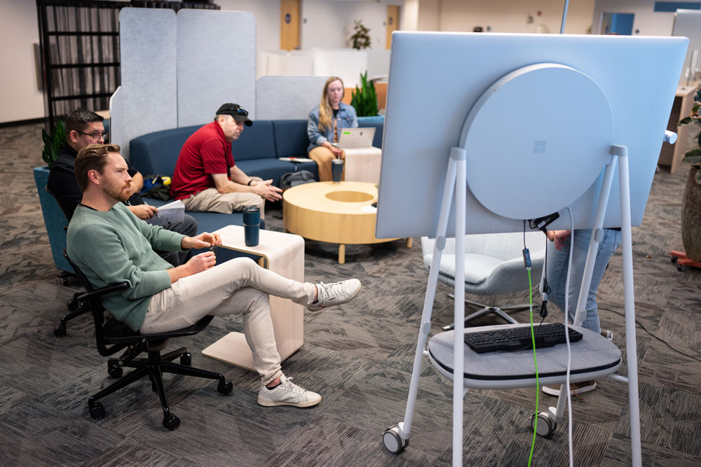 COLLABORATION STATION — From left, Clint Moore, Chris Lucero, Colin Laskar and Natalie Jung, with Strategic Facilities and Infrastructure Integration, take part in a hybrid meeting at the collaboration space in IPOC. (Photo by Craig Fritz)
