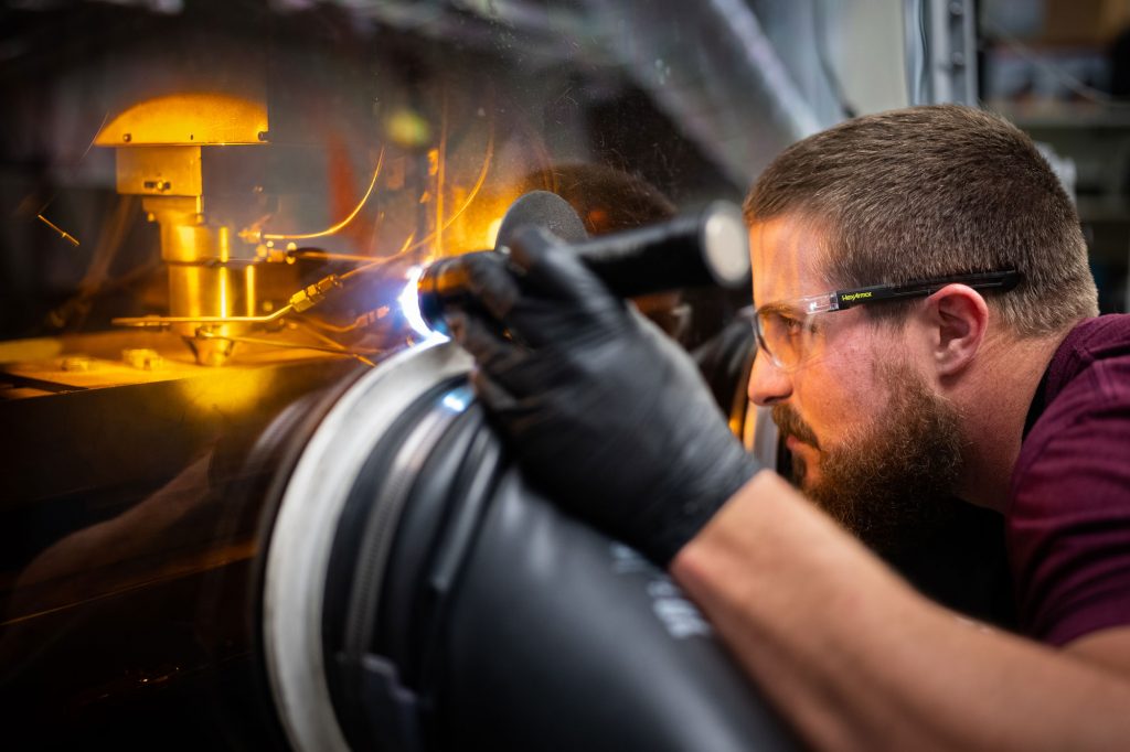 EYES ON THE PRIZE — Sandia technologist Levi Van Bastian works to print material on the Laser Engineered Net Shaping machine, which allows scientists to 3D print new superalloys. (Photo by Craig Fritz)