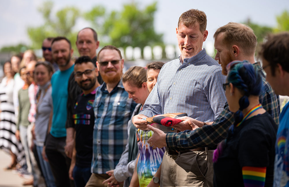 FLY THE RAINBOW FLAG — Nuclear engineer Matt Allen hands off the pride flag as it is passed down a line of participants before it is raised outside the administrative office at Sandia New Mexico. On June 1, Sandia raised the pride flag to kick off Pride Month and celebrate the LGBTQ+ staff members who help fulfill the Labs mission. (Photo by Craig Fritz)