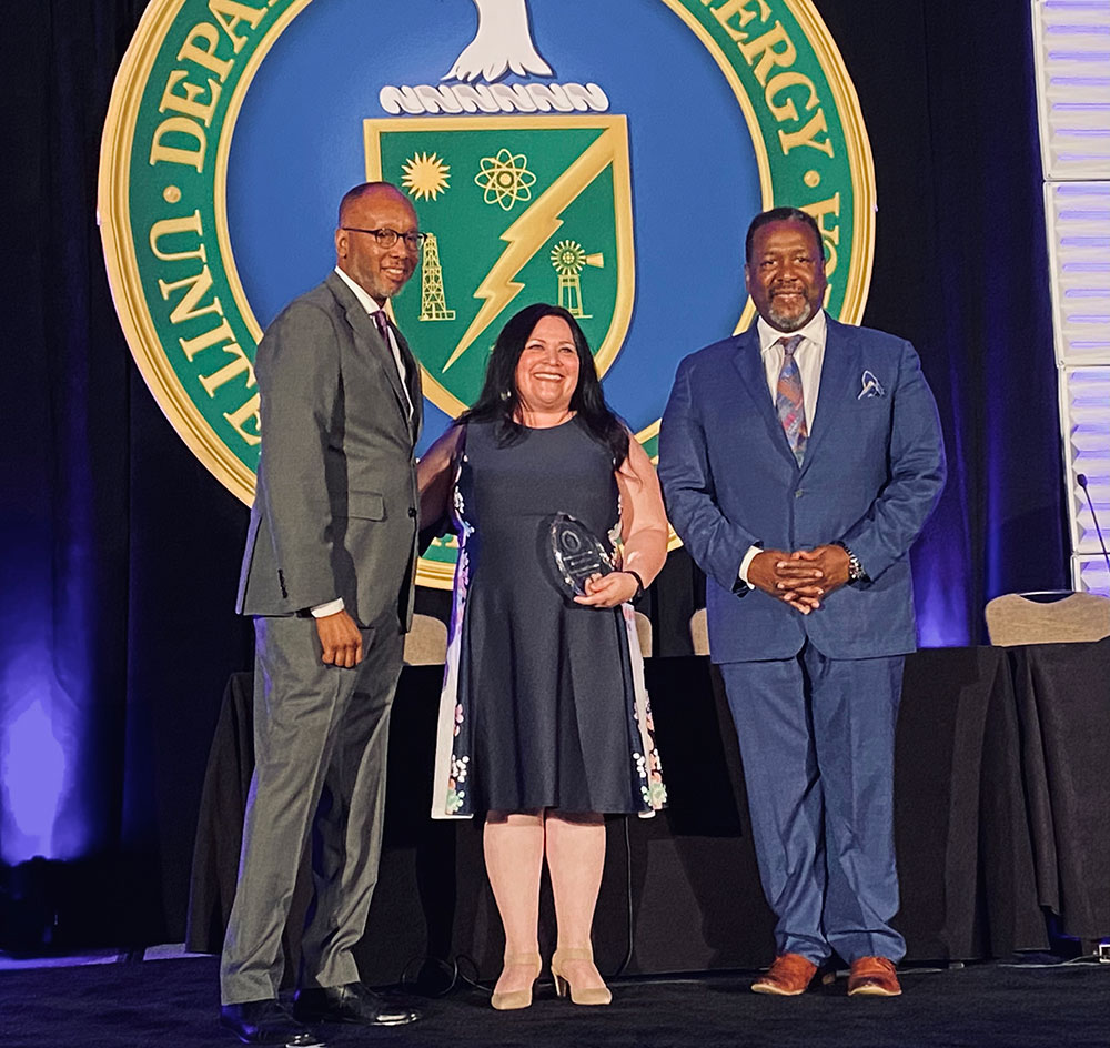 MENTOR OF THE YEAR — Sandia Mentor Protégé Program Lead Royina Lopez, center, accepts the award for DOE Mentor of the Year at a ceremony on July 11. Ron Pierce, Director of DOE Office of Small and Disadvantaged Business Utilization, left, and small-business owner Wendell Pierce presented the award. (Photo by Patricia Brown)
