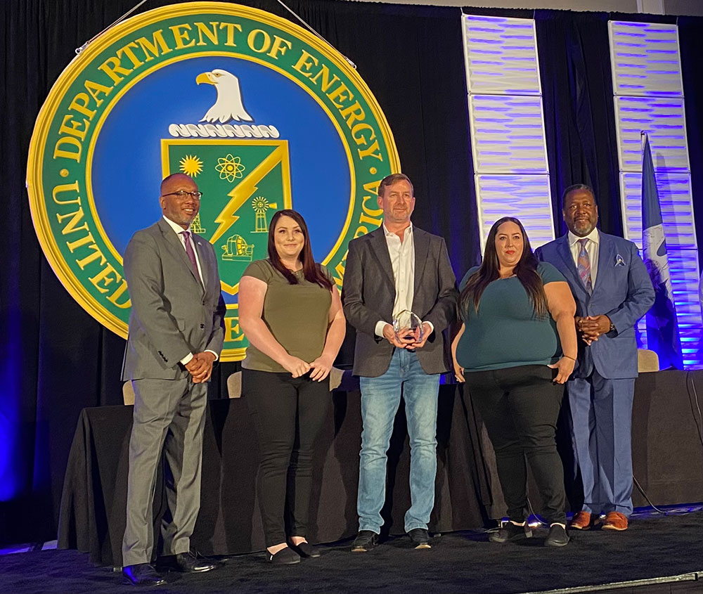 SMALL BUSINESS SUPPORTING LABS — The Wildflower International team, including Operations Manager Cheri Chandler, second from left, DOE Business Unit Director Justin Thigpen, center, and DOE Operations Senior Manager Marlena Lucero, second from right, accepts the HUBZone Small Business of the Year award. The award recognizes Wildflower’s critical support of Sandia, Los Alamos and Lawrence Livermore national laboratories. (Photo by Patricia Brown)