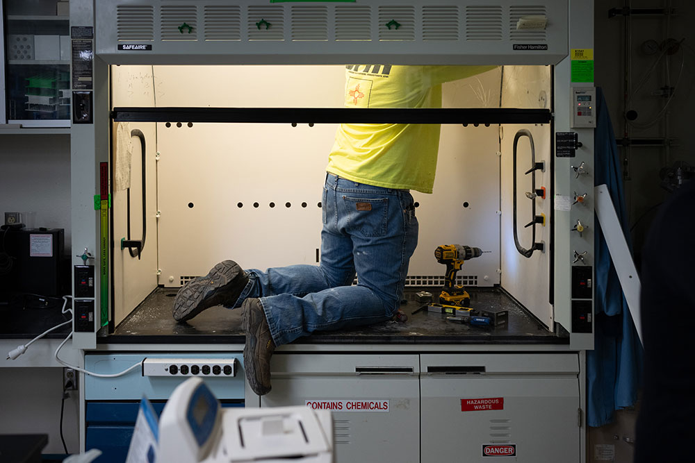 LAB UPGRADES — Contractor Callan Scoggin retrofits a fume hood in a building as part of the Smart Labs pilot program. (Photo by Craig Fritz)