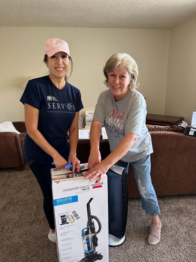WELCOME HOME — Saranam LLC Office Management Assistant Angela Walde, left, and her mother Cecilia Salas unpack a new vacuum in an apartment for a family that will move in soon. In 2023, Saranam received a $15,000 grant from Sandia to help provide stable housing to families experiencing homelessness in New Mexico. (Photo by Katrina Wagner)