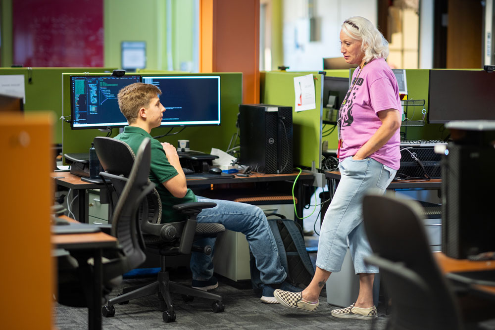 CYBER INTERN — Colette Bristol, right, the coordinator for Sandia’s Center for Cyber Defenders program, talks with intern Joel Schott in the Center for Cyber Defenders office. Colette arranges tours of interesting facilities and short technical talks so that the interns can get the most out of their summer. (Photo by Craig Fritz)