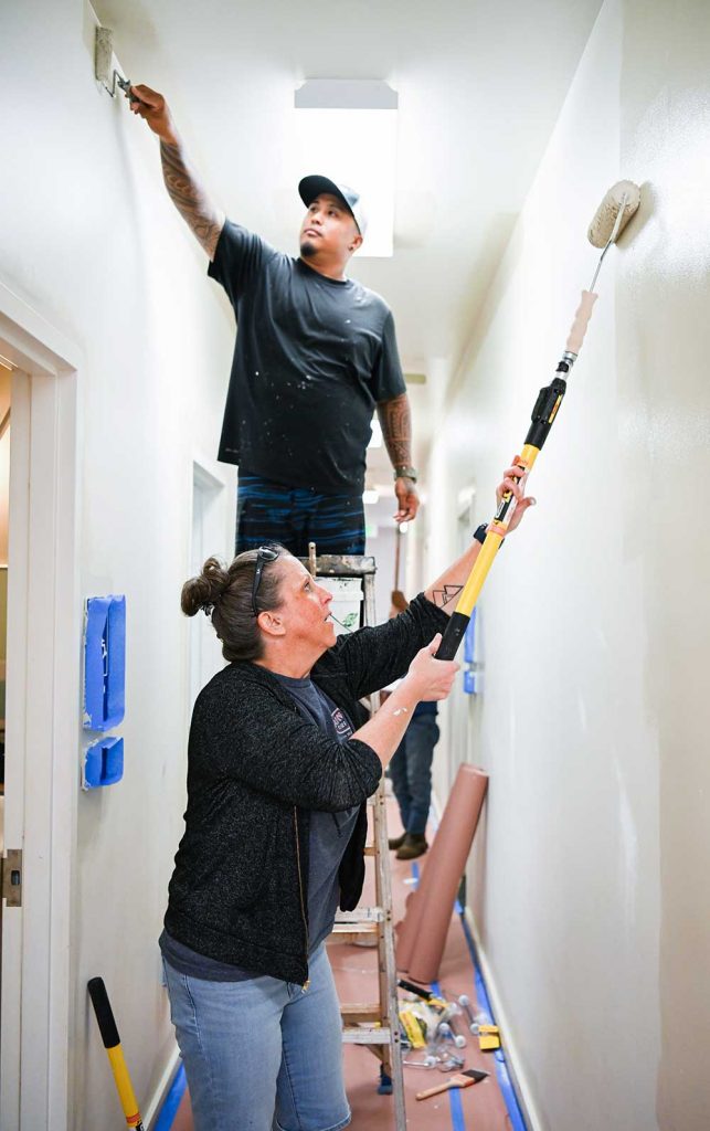 NEW HEIGHTS — Sandians Rilen Bayot, top, and Katie Jurney paint a hallway in the clubhouse of the Waimea branch of the Boy and Girls Club. A group from the Sandia Kauai Test Facility spent a day painting the clubhouse, which serves children from elementary to high school.