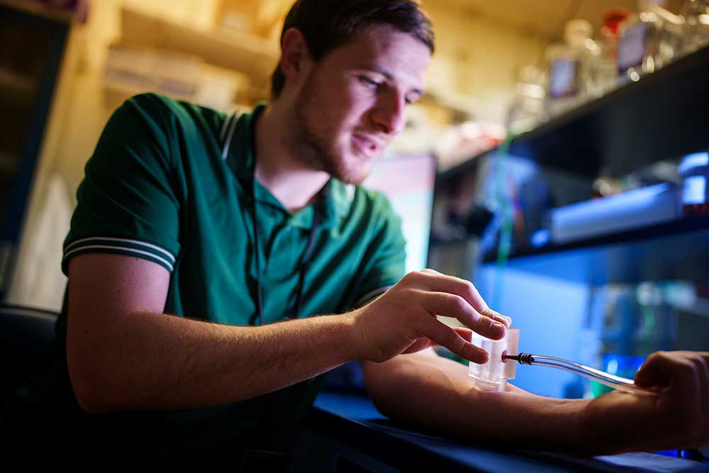 ENHANCED EXTRACTION — Engineer Adam Bolotsky demonstrates how Sandia, in collaboration with SRI, has enhanced the extraction of interstitial fluid. The improved extraction method gets more fluid in less time. (Photo by Craig Fritz)