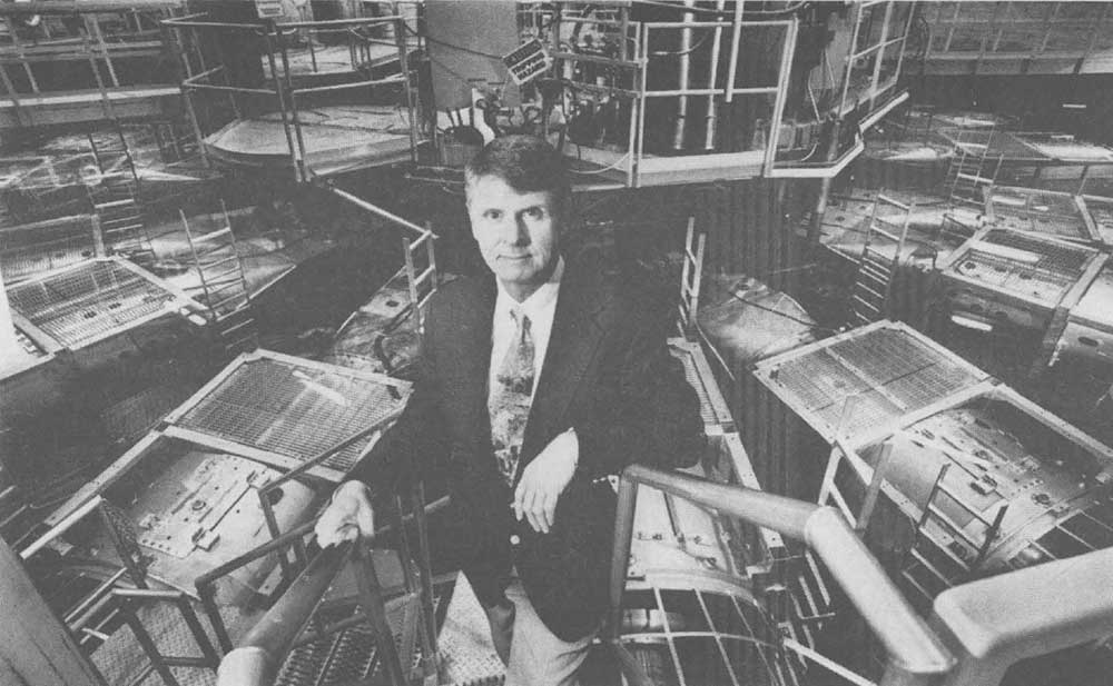 PULSED POWER PLANS — In a 1996 Lab News photo, Don Cook poses with Particle Beam Fusion Accelerator II in the background. At the time, Cook was director of the Pulsed Power Sciences Center, which later became the Z Pulsed Power Facility under his leadership. (Photo by Randy Montoya)
