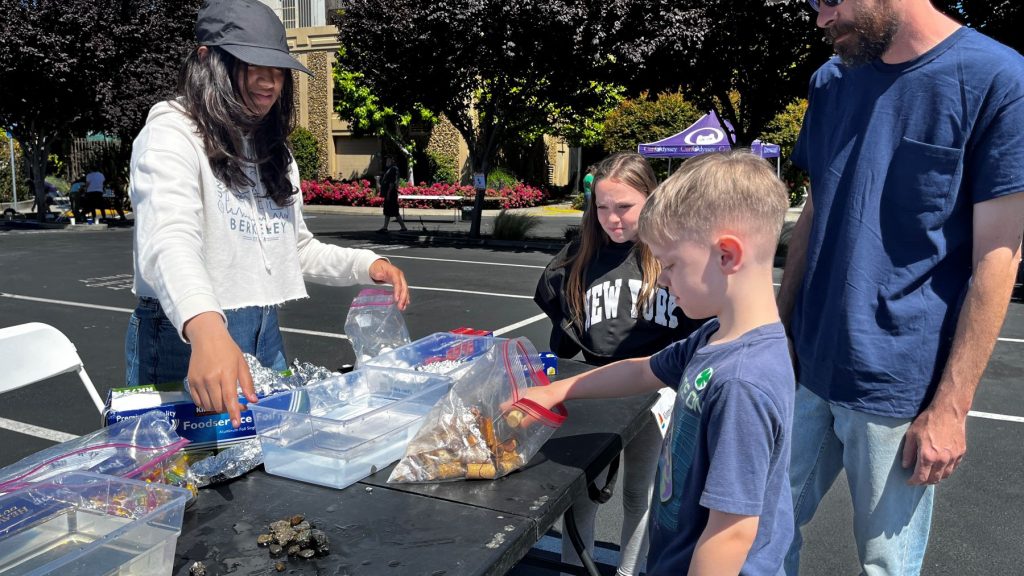 YOUNG EXPLORERS — Intern Sanjana Goyal facilitates exploration of an aluminum boat. (Photo by Michelle Walker-Wade)