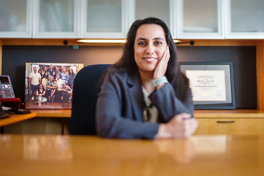 AN UNIMAGINABLE FUTURE — Del Salazar, chief financial officer and director of finance, keeps her family photo and accounting license nearby in her Sandia office. (Photo by Craig Fritz)