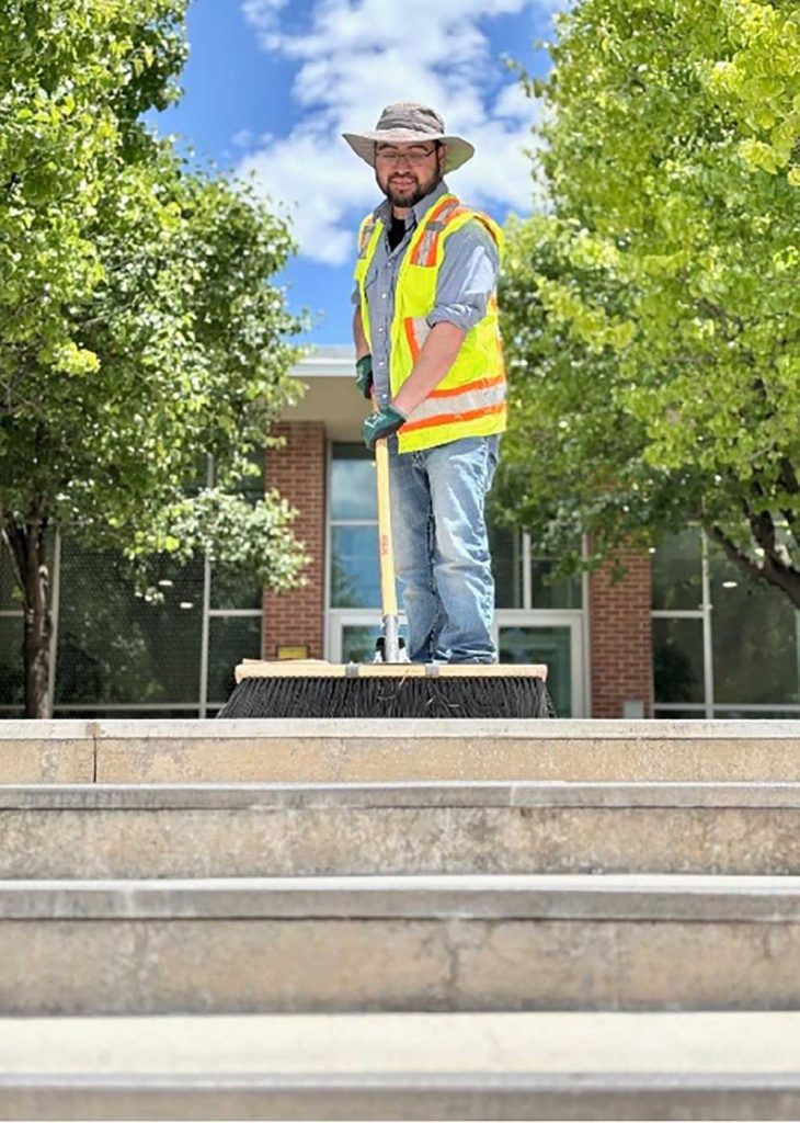 SAFER WALKWAYS — Grounds and Roads team member and gardener Dimas Silva sweeps debris from steps outside a building located in Tech Area I in Albuquerque. Dimas and his 19 teammates maintain Sandia’s New Mexico campus. Clearing debris from walking pathways helps prevents slips, trips and falls, which are a leading cause of injuries in the workplace. (Photo by James Stewart)