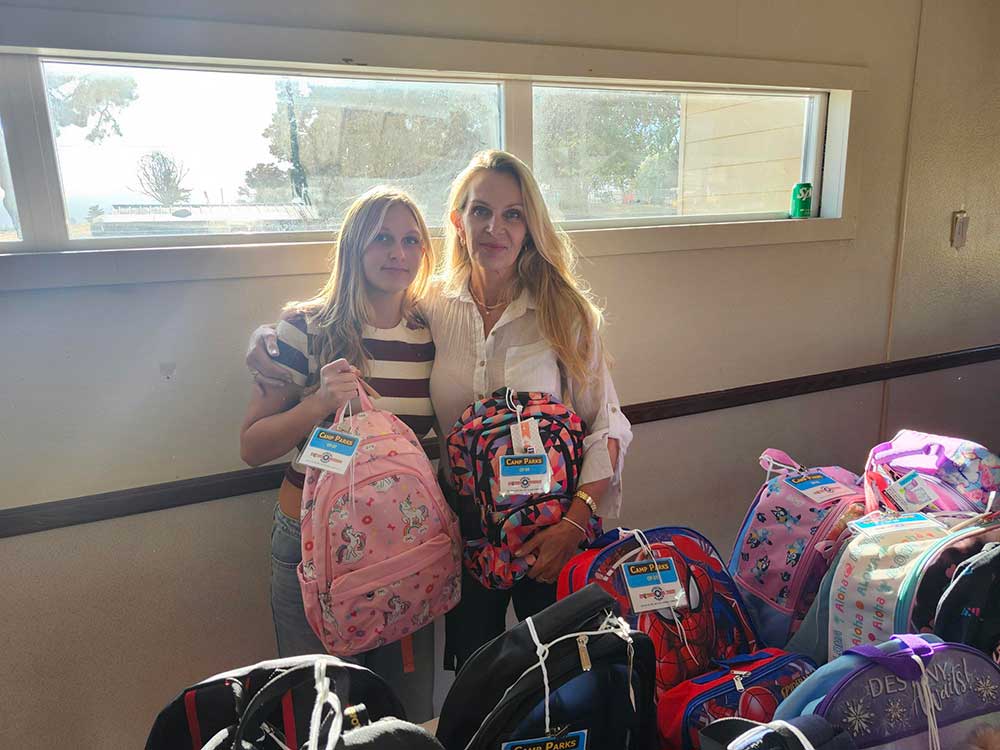 FAMILY VALUES — Rachel and Natalie distribute backpacks at the Parks Reserve Forces Training Area. Rachel also contributed 25 backpacks for distribution after school starts.