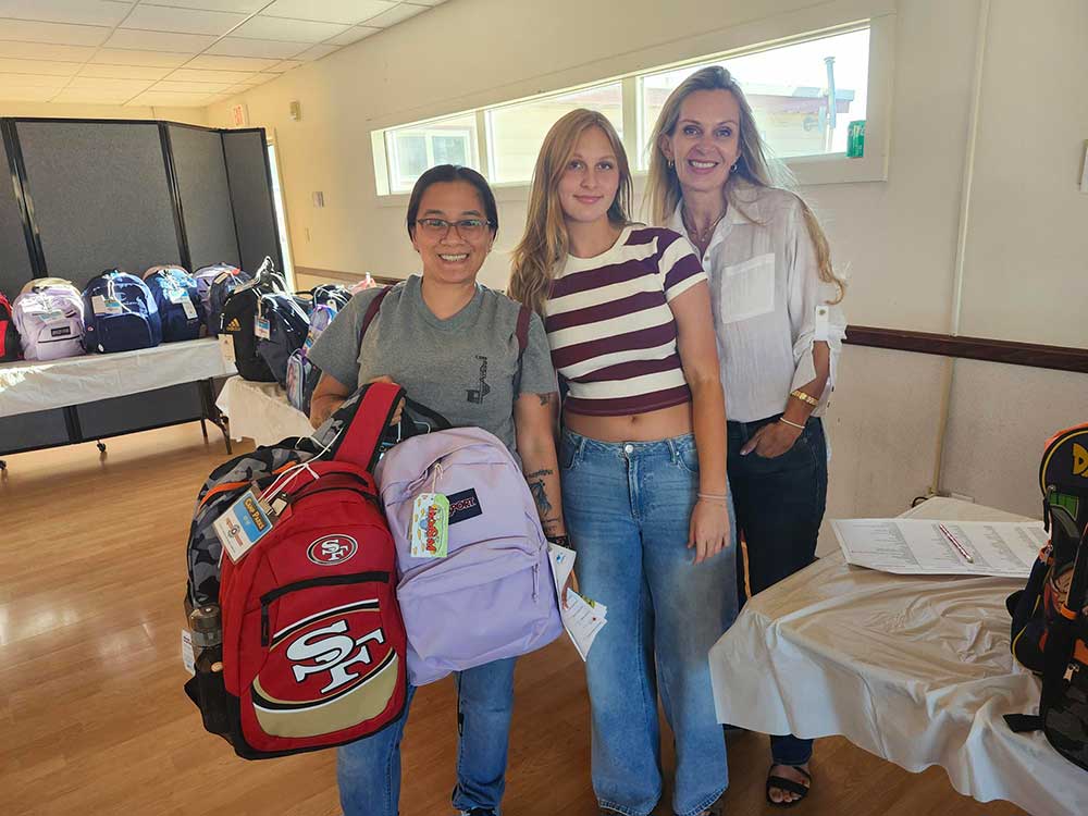 PACK IT UP — Rachel, right, and her daughter Natalie Sowell, middle, distribute backpacks to families at the Parks Reserve Forces Training Area.