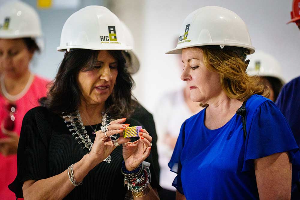 3D LESSONS — Donna Lopez and Shelly Branscom look at a 3D-printed item during a hard hat tour of Sandia’s new Center for Advanced Manufacturing and Innovation. The tour was held for Commercial Real Estate Women of New Mexico. (Photo by Craig Fritz)
