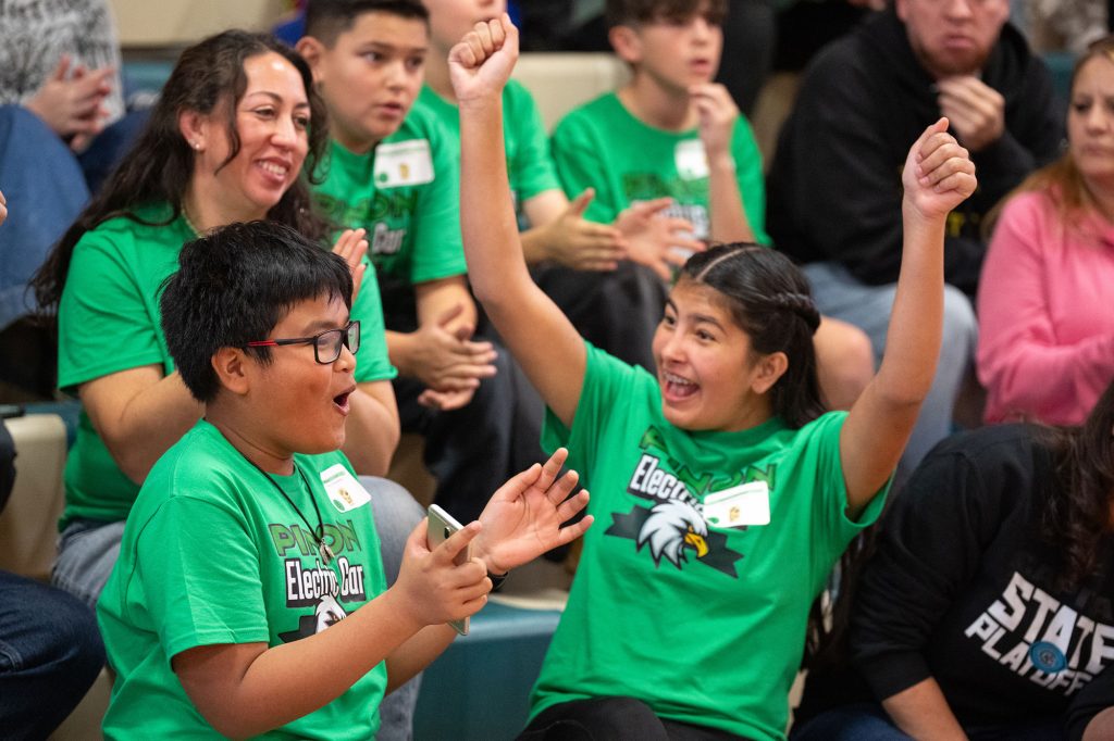 FINAL LAP — Students from Piñon Elementary School in Santa Fe, Wylone Timbal, left, and Kamryn Bachina, celebrate their advancement to the finals of the New Mexico Electric Car Challenge. The event was sponsored by Sandia and Los Alamos national laboratories and hosted at Kennedy Middle School in Albuquerque on Nov. 15. (Photo by Craig Fritz)