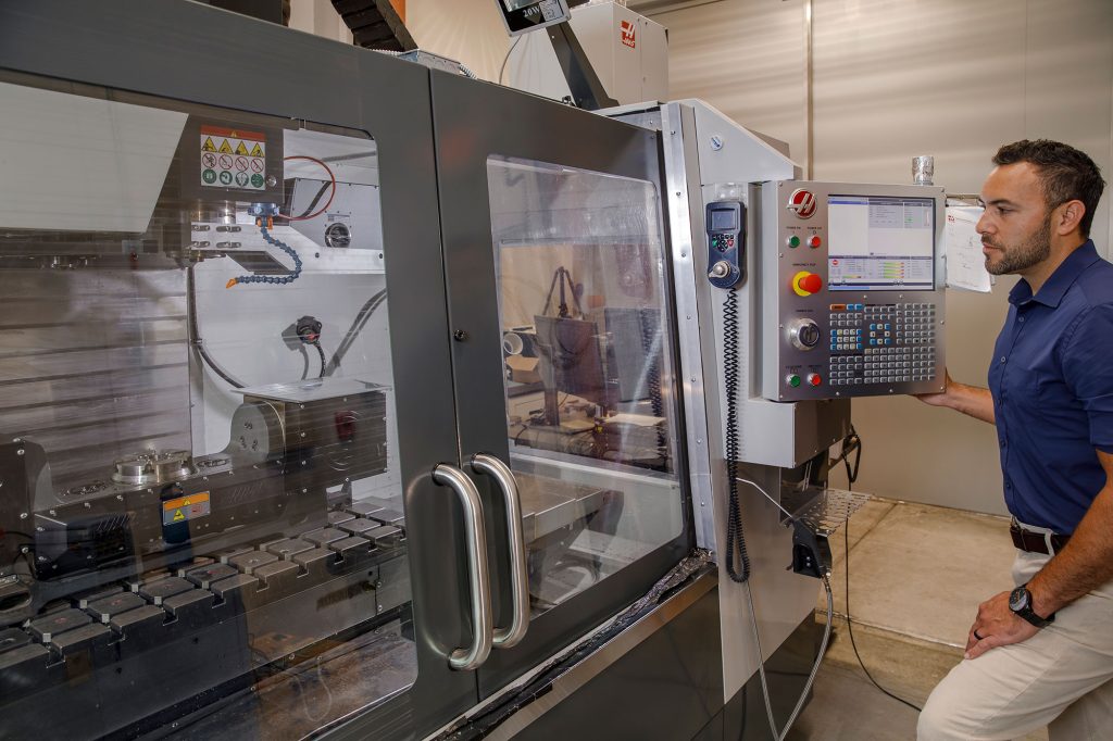 PATCH WORK — Isaac Aviña uses a laser etching printer at Sandia California to create a disposable dosimeter patch. He and the team have used the machine to create thousands of prototypes during the development cycle. (Photo by Spencer Toy)