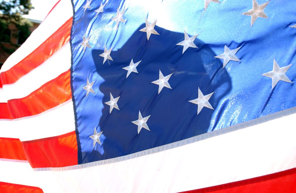 <strong>DAY OF UNITY AND MOURNING</strong> — Flags across the nation were lowered to half-staff the morning after the Sept 11 attacks. Pictured here is Sandia Security Police Officer Buster Dial lowering the flag in front of Bldg. 800. (Photo by Randy Montoya)